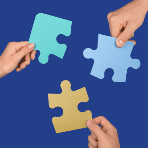 three hands holding separate puzzle pieces coming together